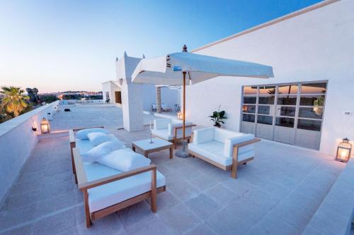a patio with white furniture and an umbrella at Tenuta Mosè Charming House&Relais Gallipoli in Gallipoli