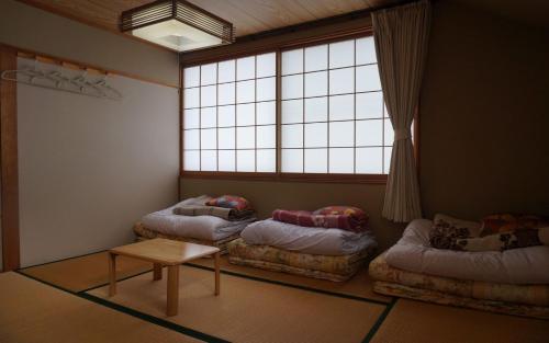 安曇野市にあるあづみの池田ゲストハウスのベッド2台、テーブル、窓が備わる客室です。