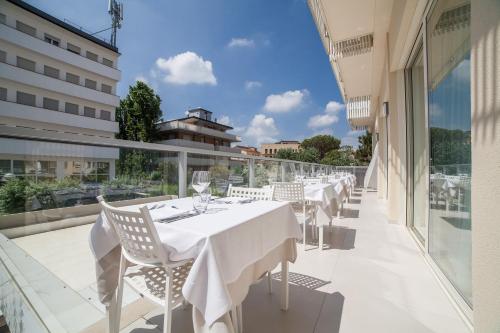 a restaurant with white tables and chairs on a balcony at Hotel Majestic in Milano Marittima