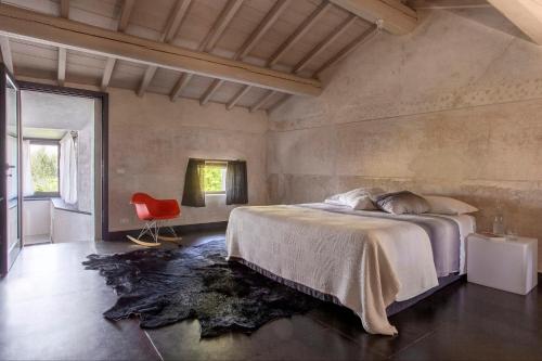 a bedroom with a large bed and a red chair at Corte Mainolda in Castellucchio