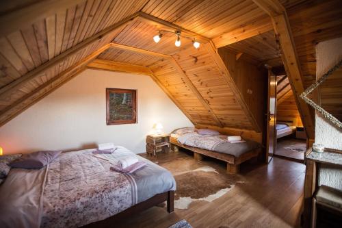 a bedroom with two beds in a wooden attic at Kuća za odmor "Neralić" in Josipdol