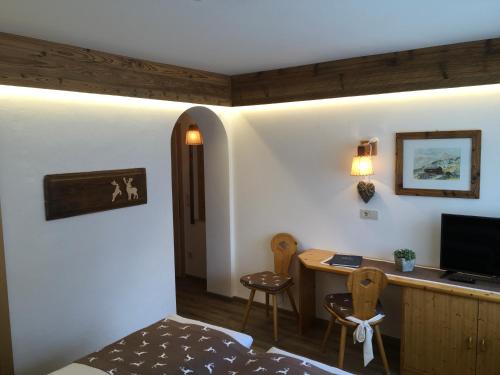 a bedroom with a bed and a desk with a television at Garni Raetia in Corvara in Badia