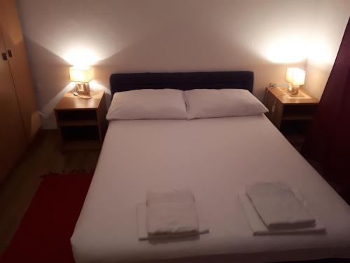 a bedroom with a white bed with two lamps on both sides at Apartman Miro in Cavtat