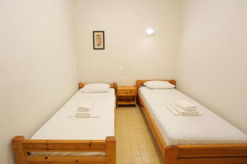 two beds in a small room with white sheets at Panorama Plataria Ionio Studios&Apartments in Plataria