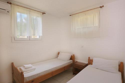 two beds in a room with two windows at Panorama Plataria Ionio Studios&Apartments in Plataria
