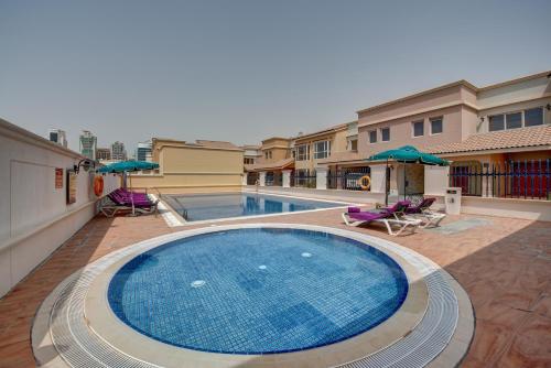 a swimming pool with chairs and umbrellas next to a building at J5 Villas Holiday Homes Barsha Gardens in Dubai