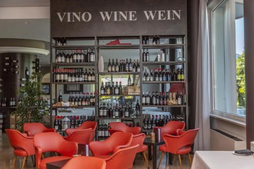 a restaurant with red chairs and a wine wall at Hotel Della Torre in Stresa