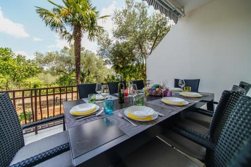 a table with plates and glasses on a balcony at Guesthouse Klara in Duba Stonska