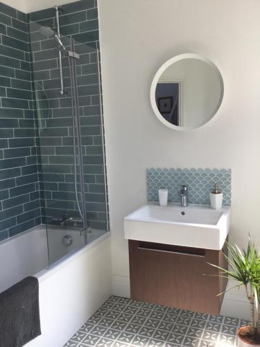 a bathroom with a sink and a shower and a mirror at Margate Holiday Apartment in Margate
