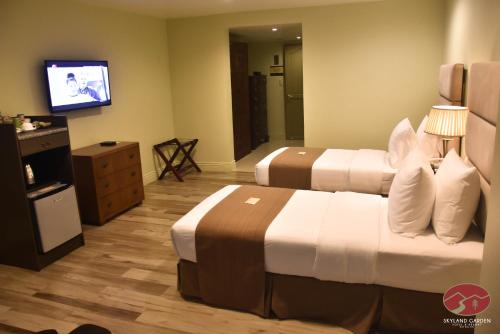 a hotel room with two beds and a flat screen tv at Skyland Garden Hotel and Resort in Baguio