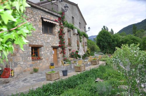 a stone building with tables and chairs in front of it at Casa Rural Molí de Fòrnols in Fornols