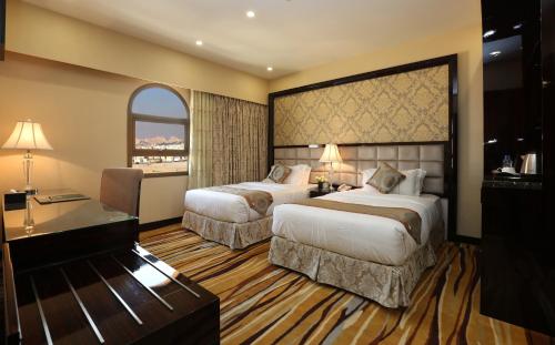 a hotel room with two beds and a desk at Al Muhaidb Residence Al Ahsa in Al Ahsa