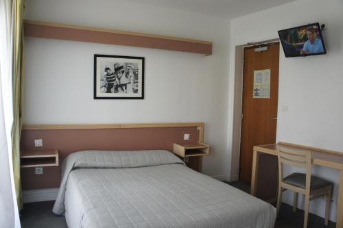 a bedroom with a bed and a desk in it at Hôtel Edgar Quinet in Paris