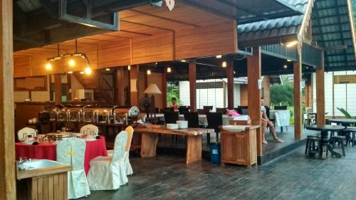 a restaurant with wooden tables and chairs and a person at Bayu Lestari Island Resort in Mersing