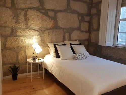 a bed in a room with a stone wall at Oporto Foz House close to the beach in Porto