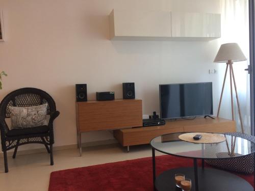 Una sala de estar con un televisor de pantalla plana y una silla. en Harmony, en Sveti Stefan