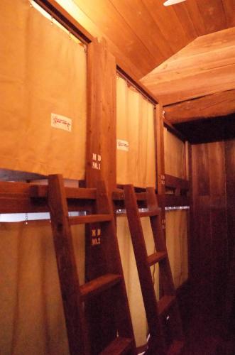 two wooden chairs sitting in a room with a window at 古民家ゲストハウス ナマケモノ in Ōno