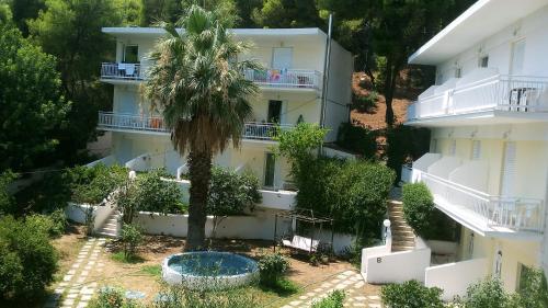 an apartment building with a palm tree in front of it at Zontanos Studios & Apartments in Poros