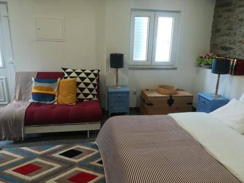 ein Schlafzimmer mit einem Bett, einem Sofa und Fenstern in der Unterkunft A Tasca in Vila Real