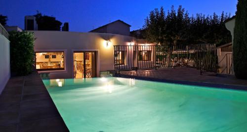 a swimming pool in front of a house at night at Logis Hotel Le Nouvel in Portes-lès-Valence
