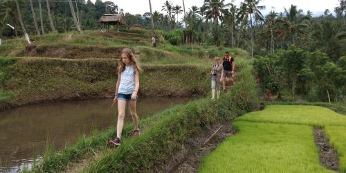 a young girl walking across a bridge over a river at Mandhasativa Homestay in Singaraja