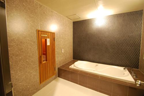 Hotel Free Style Okayama في أوكاياما: حمام مع حوض استحمام وحائط بلاط