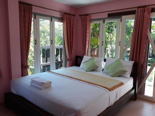 Schlafzimmer mit einem großen weißen Bett und Fenstern in der Unterkunft Wansawang Homestay in Pran Buri
