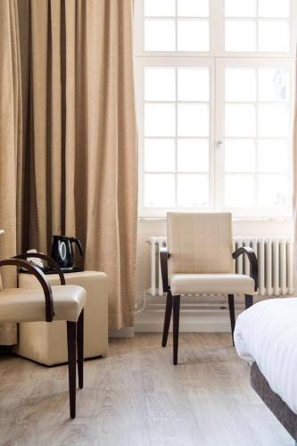 a bedroom with two chairs and a bed and a window at Kasteel Pietersheim Maastricht - Lanaken in Lanaken