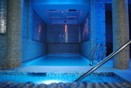 a large swimming pool in a building with blue lighting at Sole Mio Apartment & Wellness in Herceg-Novi
