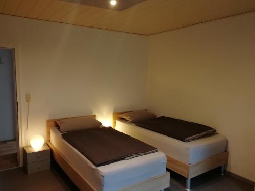 sypialnia z 2 łóżkami i lampką na ścianie w obiekcie Apartment am Park - Erica w mieście Schneverdingen
