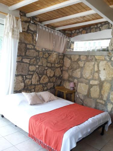a bedroom with a bed in a stone wall at Leucate,dans la verdure,studio caverne en pierre dans propriété sécurisée in Leucate