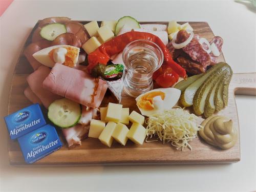 a tray of food with cheese and vegetables on it at Pension Garni Appartement Ortner in Sankt Johann in Tirol