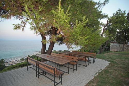 a row of wooden benches sitting next to the ocean at Sea View Apollo Apartments & Studios in Afytos in Afitos