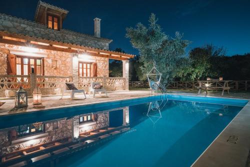 a villa with a swimming pool at night at Alegria Villas Complex in Vasilikos