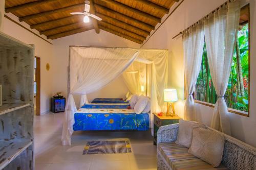 a bedroom with a canopy bed and a couch at Pousada do Bosque in Trancoso