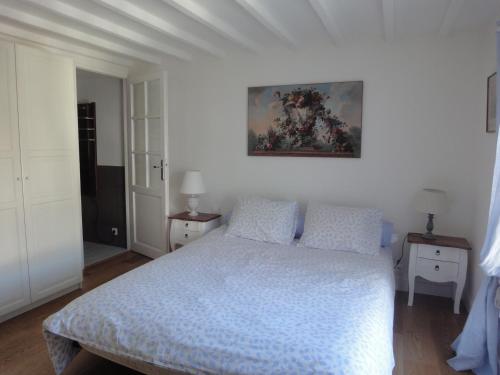 Saint-AugustinにあるCouleurs et jardinのベッドルーム1室(ベッド1台付)が備わります。壁には絵画が飾られています。