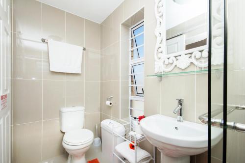 a white bathroom with a toilet and a sink at King Guest Lodge in Port Elizabeth