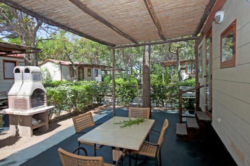 un patio con tavolo, sedie e griglia di Camping Capalbio a Capalbio