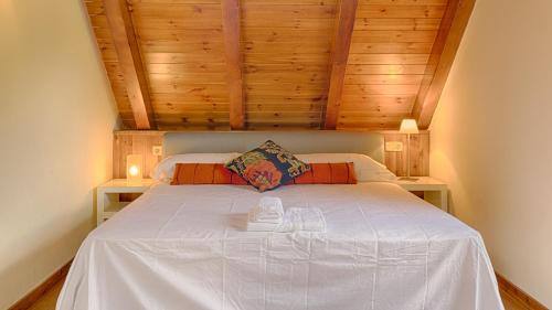 a bedroom with a white bed with wooden ceilings at Saplan Real Estate TERMAS in Les