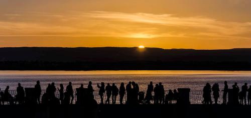 a group of people standing near the water at sunset at Apollo B&B in Siracusa