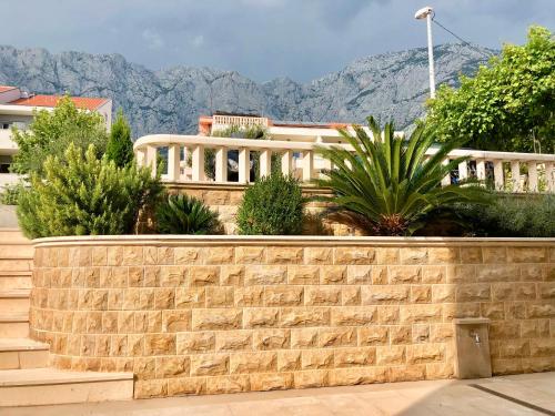 a brick retaining wall with mountains in the background at Apartment Dalmatien Traumhaus in Makarska