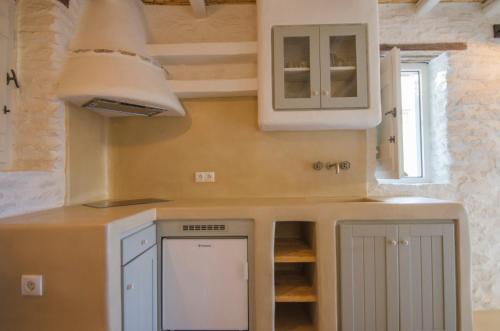 a kitchen with white cabinets and a sink at Yialos Ios Hotel in Ios Chora