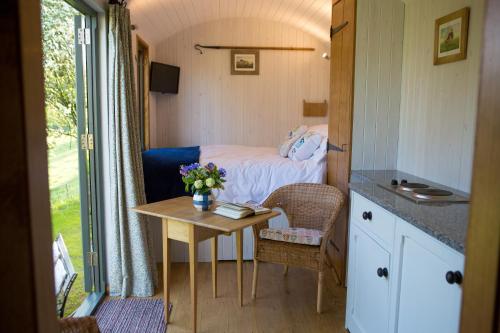 Habitación pequeña con cama y mesa en GoldenValley Shepherd's Hut en Dorstone