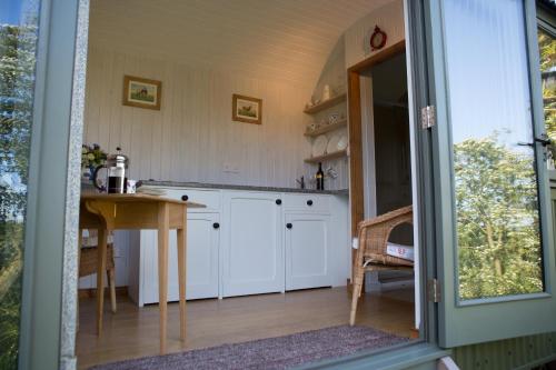 a kitchen with white cabinets and a table at GoldenValley Shepherd's Hut in Dorstone