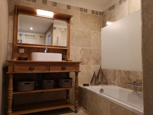 La salle de bains est pourvue d'un lavabo, d'une baignoire et d'un miroir. dans l'établissement Entre Vignes et Collines, à Méthamis