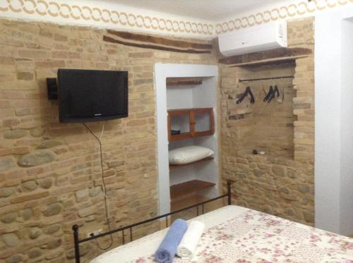 a bedroom with a tv on a brick wall at Pantorano rooms in Spinetoli