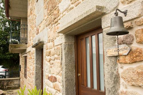 a bell on the side of a building with a door at Casal de Cereixo in Tufiones
