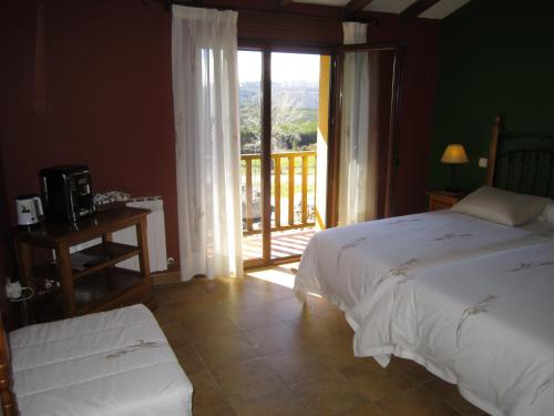 a bedroom with a bed and a window with a balcony at Hotel Rural La Dehesilla in Barajas de Gredos