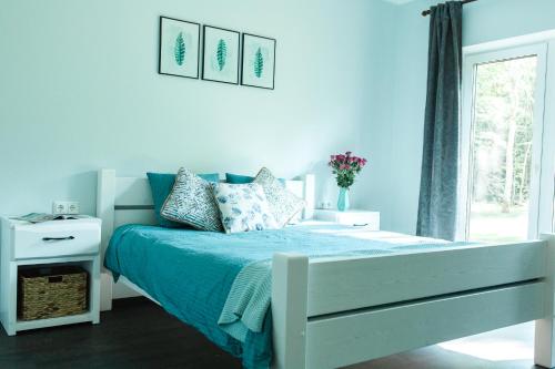 a white bedroom with a bed with blue sheets and a window at The Peaceful Vacation in Muratsi