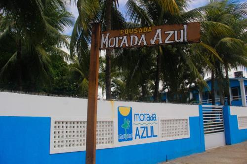 a street sign in front of a wall with palm trees at Pousada Morada Azul in Porto De Galinhas